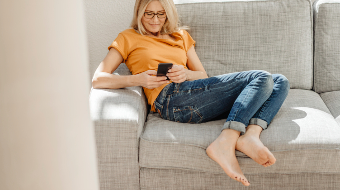 Woman with glasses checkin his phone on a sofa